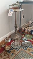 Full view of floor-standing ashtray stand with amber glass insert and smaller ashtrays on carpet