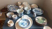 Complete display of all dishes on table including Wedgwood and Johnson Brothers plates, platters, bowls, and small ginger jar.