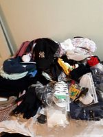 Top view of assorted adult hats, socks, and gloves piled on a surface with some items still in packaging.
