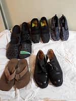 Full view of 6 pairs of men's shoes including black crocs, brown sandals, sneakers, and leather shoes