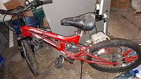Full side view of the red Mongoose 20 inch bike showing frame, tires, pedals and seat.
