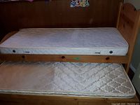 Mother wood single bed with mattress on top and pull-out child bed below with mattress and drawers.