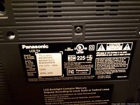 Close-up of the TV's information label showing brand Panasonic, model TC-L32G1, serial number, power requirements, manufacture date April 2009, and safety certification labels.