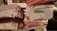 Photo showing two stacks of assorted towels mostly white, brown, beige, some with red stripes and orange-red colors