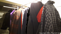 Photo showing multiple coats and jackets hanging on a rack, including plaid, solid colors, and mixed fabrics.