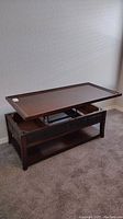 Photo showing the coffee table with the top lifted, revealing internal storage and lower shelf.