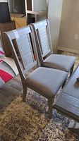 Photo showing two dining chairs from a side angle with visible upholstery and wooden frames.