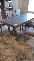 Full view of the faux wood rectangular dining table with chairs around it showing the entire tabletop and base structure.