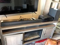 Wide shot showing Samsung HW-N650 soundbar on stand beneath TV, Pioneer SX-255R receiver on shelf next to a Samsung subwoofer.
