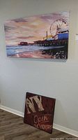 Photo of large canvas print mounted on wall showing pier and Ferris wheel scene, colorful sunset sky and ocean