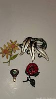 Four vintage floral enamel brooches arranged on a flat surface.