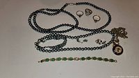 All jewelry items arranged on a white surface, showing variety of necklaces, rings, earrings, and bracelet.