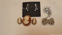 Full view of all four pieces laid out on a beige surface with black earring card