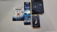 Lot overview showing four new items: Lexar USB jump drive, Oral-B brush head, MTV wireless earbuds box, and Yamaha saxophone reed box.