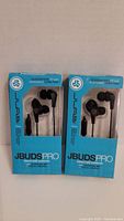 Front view of two sealed Jbuds Pro earbud packages, showing black earbuds and packaging information.
