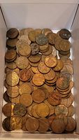 Top-down view of a box full of mixed U.S. and Canadian pennies showing a variety of coin conditions and tarnish.