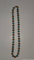 Full view of the 18 inch costume jewelry necklace laid flat showing alternating blue and gold-tone textured beads.