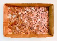 Cardboard box filled with many Canadian pennies, mostly copper colored coins.