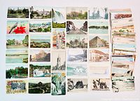 Overview of approximately 60 colorful and black & white antique postcards laid out, featuring buildings, nature scenes, and waterfalls.