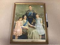 Full view of framed 1939 Royal Family print showing the King, Queen, and two daughters, with pen for scale.