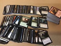 Photo showing stacks of more than 500 Magic the Gathering cards assorted by color and type laid out on a surface.