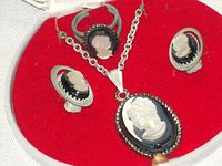 Close-up of white cameo ring and earrings on red velvet