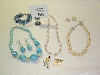 Full lot layout showing all the jewelry items on a white surface including necklaces, earrings and brooches.