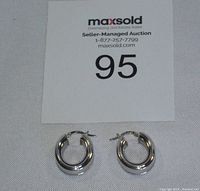 Pair of earrings front view on fabric background with auction card