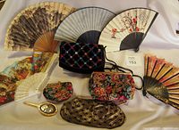 View of the five folding hand fans and five evening bags laid out together.