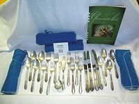 Full set of 20 utensils laid out on cloth backdrop with cloth rolls and certificate