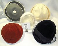 Photo showing all four vintage hats and feather headband together laid on white background.