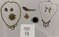 Full lot showcasing two rhinestone necklace sets, earrings, and three additional brooches arranged on white fabric.