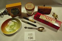 Full lot view showing various items including the clock, spoons, pens, bowl, pipe box, and ticket