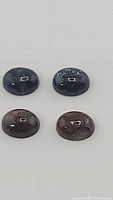 Four oval cabochon natural pietersite stones, two blue and two coffee brown, polished and smooth surface.