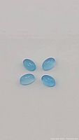 Four natural oval blue onyx cabochons arranged on a neutral background showing size, color, and surface condition.