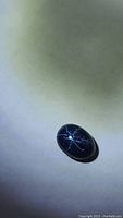 Close-up photo of the oval blue star sapphire clearly showing the 6-ray star asterism in white light.