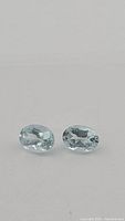 Close-up photo of the two natural oval aquamarine gemstones showing their cut and clarity.