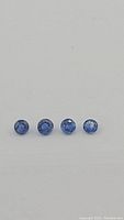 Four round cut blue kyanite gemstones of varying tones from royal blue to cornflower blue, laid out in a row