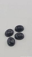 Close-up photo of 4 polished natural blue pietersite gemstones showing color and chatoyancy.