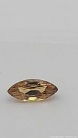 Close-up view of the marquis cut golden champagne colored zircon gemstone showing faceting and natural color.