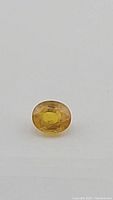 Close-up of canary yellow sapphire gemstone showing oval faceted cut and vibrant yellow color.
