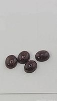 Four natural coffee brown Pietersite oval cabochon gemstones viewed close up showing surface and luster.