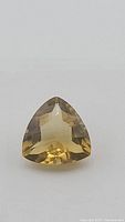 Front view of the golden citrine gemstone showing trillion checker cut and transparency.