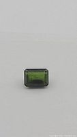 Close-up detailed photo of the green tourmaline gemstone, emerald cut, showing clarity and color.