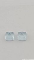 Close up photo of the pair of soft blue sugarloaf cut aquamarine gemstones side by side on white background