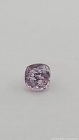 Close-up photo showing the cushion cut natural pink spinel gemstone with visible internal features and pale pink hue.
