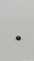 Blue-green oval sapphire on white background, faceted surface, natural inclusions visible.