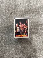 Front view of a 1985 WWF wrestling card showing three wrestlers, one shirtless wearing a championship belt, labeled 'IN THE CORNER'.