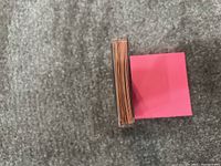 Top-down view of a stack of baseball cards tightly packed in a clear plastic case on a gray carpeted surface.