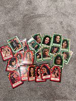 Photo showing 19 colorful Charles Angels collectible sticker cards featuring portraits of TV show characters with names and decorative stars around the edges. Cards have red or green backgrounds.
